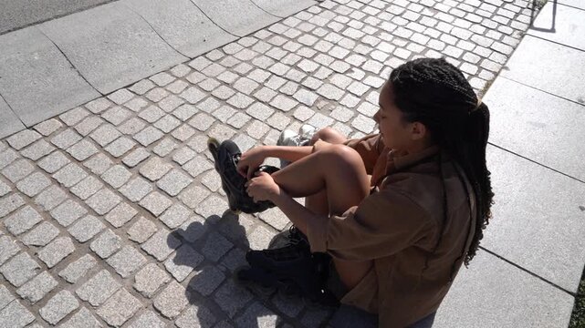 Young woman with braids putting on rollerblades