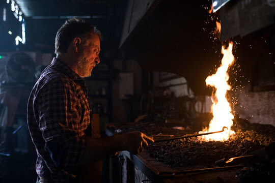 Blacksmith working at forge in his workshop