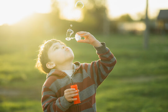 Joyful childhood moment blowing a soap bubble outdoors at sunset
