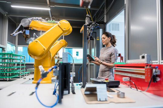 Businesswoman checking industrial robot in high tech company