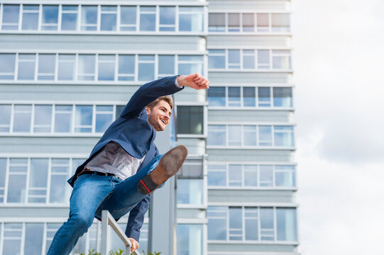 Happy young businessman crossing railing in the city