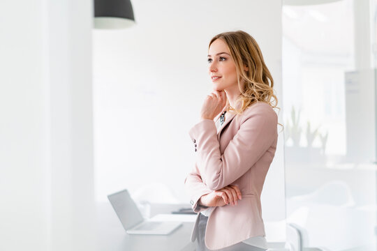 Businesswoman with hand on chin contemplating at office