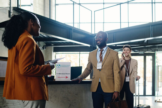 Businesswoman welcoming colleagues at reception desk in convention center