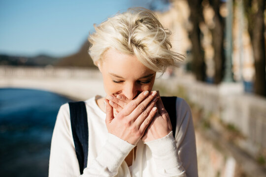 Italy, Verona, blond woman covering mouth with her hands
