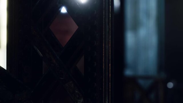 A wooden panel stands as light enters from the outside, creating a contrast with the darker area inside. The setting seems to be a room with soft lighting and textures.