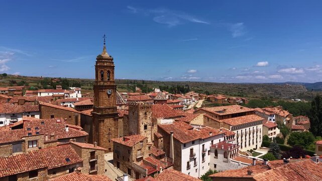 Elevated view of La Iglesuela del Cid historic village, ornate baroque bell tower rising above terracotta rooftops, stone and whitewashed buildings, Maestrazgo region, Teruel, Aragon, Spain