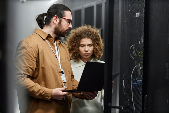 Young engineers checking servers with laptop in data center