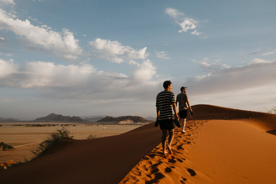 Namibia, Namib desert, Namib-Naukluft National Park, Sossusvlei, two men walking on Elim Dune at sunset