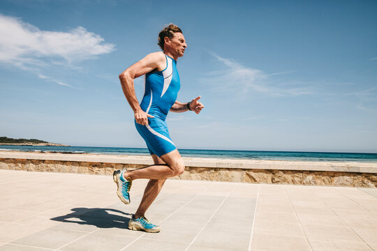 Spain, Mallorca, Sa Coma, triathlet running along beach promenade