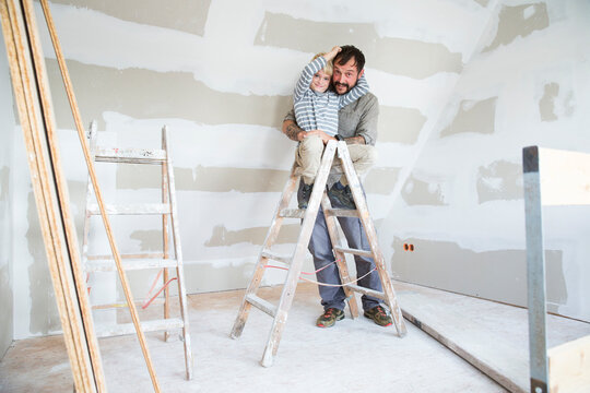 Portrait of happy father and son working on loft conversion