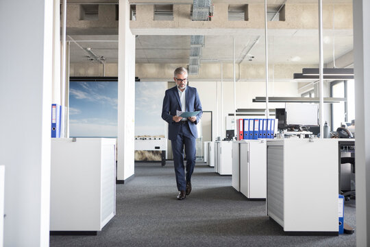 Businessman walking in office holding documents