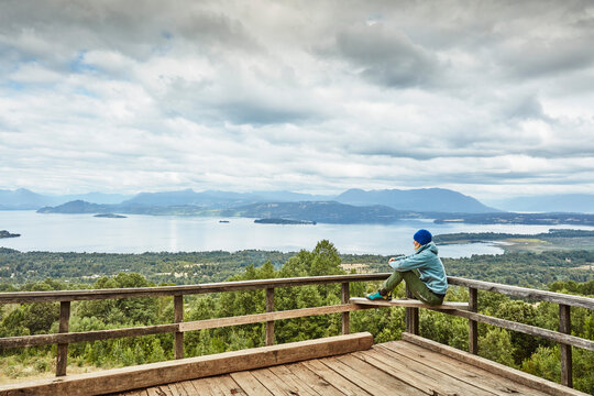 Chile, Puren, Nahuelbuta National Park, woman sitting on observation terrace overlooking the lake