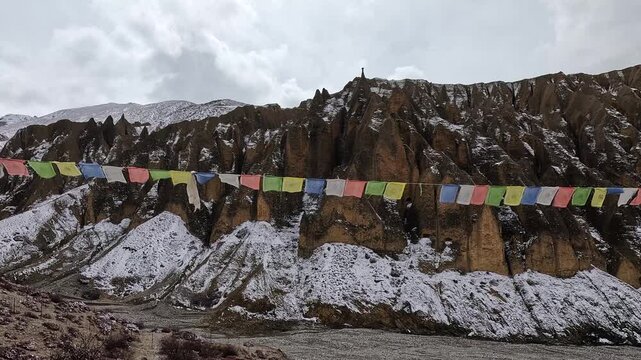 Prayer flags strung below snowy cliffs at Luri Gompa (Luri Gumba), Upper Mustang, Nepal