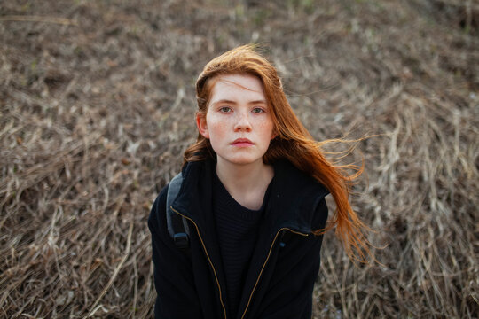 Portrait of a redhead with a backpack standing outdoors in a field
