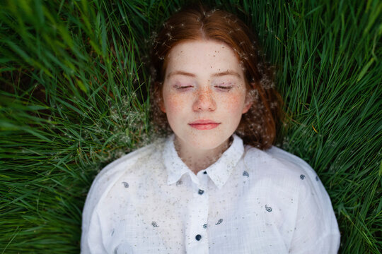 Woman with red hair enjoys summer nature in green grass