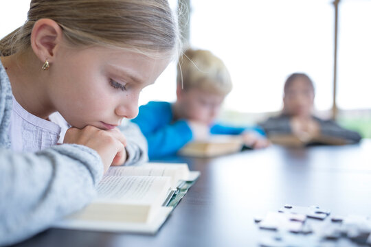 A diligent schoolgirl engrossed in reading during her break in the school's cozy break room