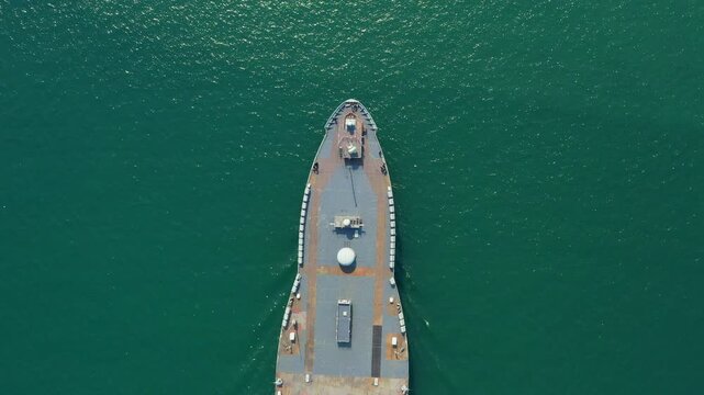 Stunning aerial shot reveals majestic Amphibious Assault Ship. Navy aircraft carrier floating serenely on calm, dark teal ocean, demonstrating its power and capabilities from above.