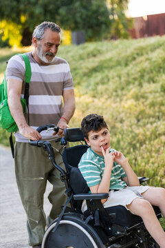 Grandfather pushing child with cerebral palsy in wheelchair