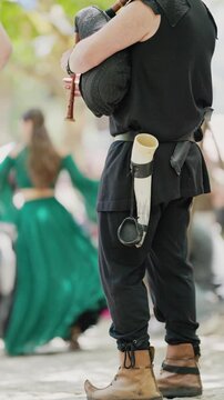Musician plays bagpipes at a festival in a park during the afternoon