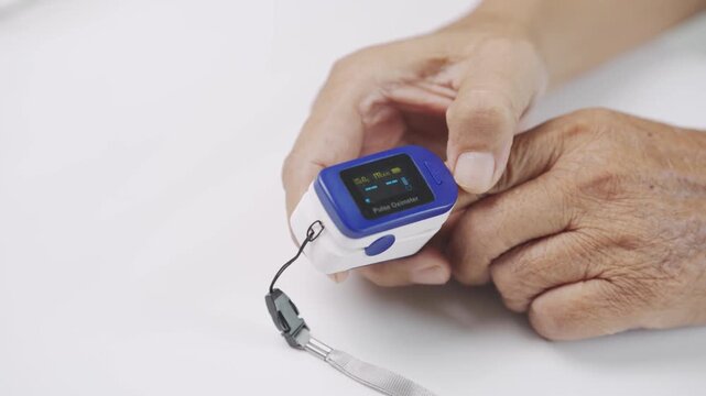 Close up of a caregiver placing a pulse oximeter on a senior finger to measure blood oxygen saturation and pulse rate, representing home healthcare, elderly care, medical monitoring, and wellness.