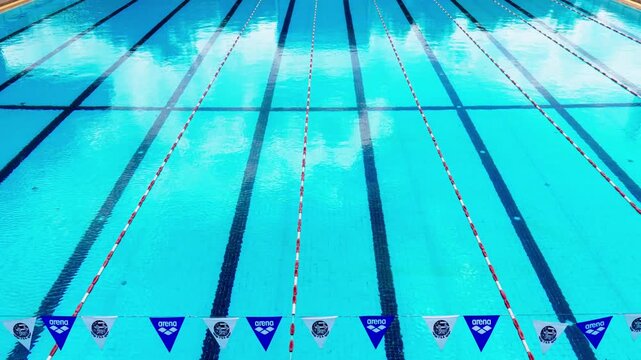 The High angle view of an empty outdoor of olympic size swimming pool with blue water and black lane lines background	