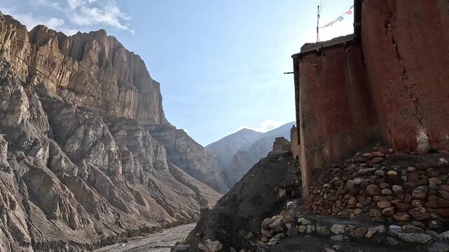 Wide opening shot of Tetang monastery with red walls and canyon landscapes in the background, Tetang, Upper Mustang, Nepal