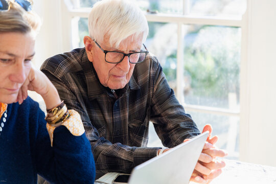 adult daughter helping her elderly father with his finances using laptop