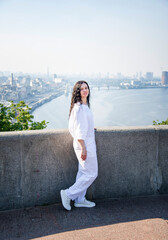Fototapeta premium young beautiful brunette romantic smiling woman in white summer suite standing on a bridge in Kyiv 