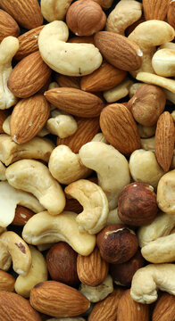 Detailed view on almond and cashew nuts in big pile on table close up