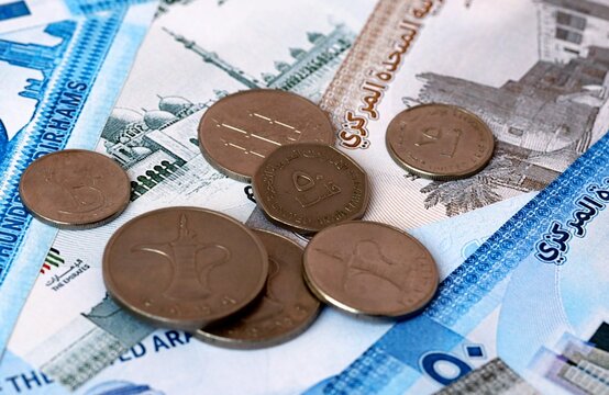 UAE dirham money banknotes and coins on table. United Arab Emirates cash bills of AED currency