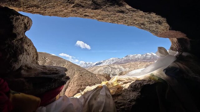 revealing view through Cave opening khata scarves snow peaks Jhong Chhoser cave Upper Mustang Nepal
