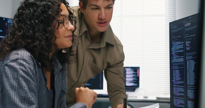  Hispanic man and woman programmers analyze code on multiple monitors together focusing on data analysis AI models database and secure application development during a team project