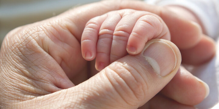 Unconditional love with trust and protection for a baby gently holding an adult's finger