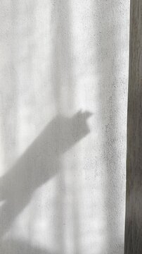 Shadow of a hand flipping book pages on a brutalist concrete wall in soft daylight. Minimal footage for publishing, education, editorial, mindfulness, and luxury lifestyle projects.