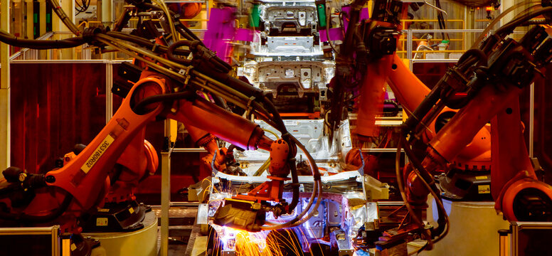 Robotic arms in an automobile manufacturing plant are performing automated tasks.