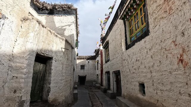Narrow walled alley whitewashed houses carved window Lo Manthang Upper Mustang Nepal