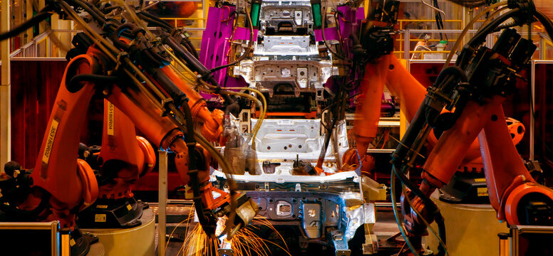Robotic arms in an automobile manufacturing plant are performing automated tasks.
