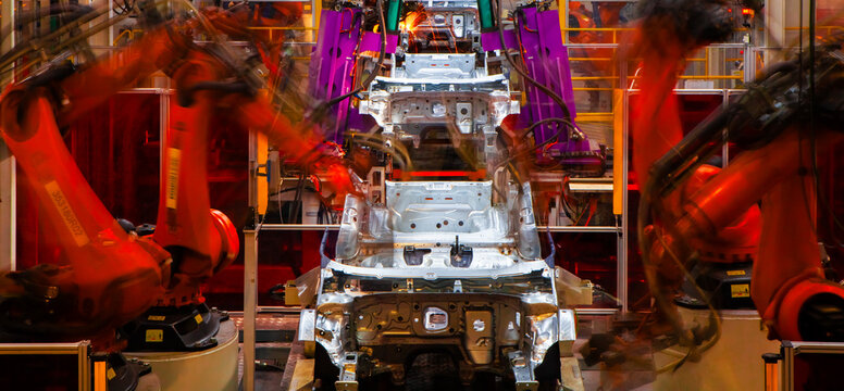 Robotic arms in an automobile manufacturing plant are performing automated tasks.
