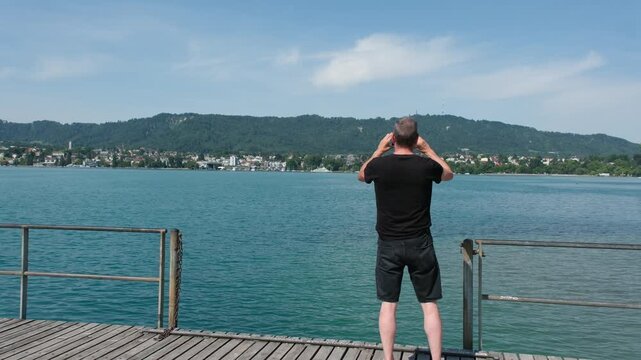 Fotografie mit Mobiltelefon, ein Mann Fotografiert das Panorama in Z&uuml;rich in der Freizeit und hofft auf eine gute Bildqualit&auml;t von den Fotos
