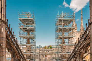 Fototapeta premium Renovation scaffolding covering the gothic spires on the roof of Milan Cathedral.