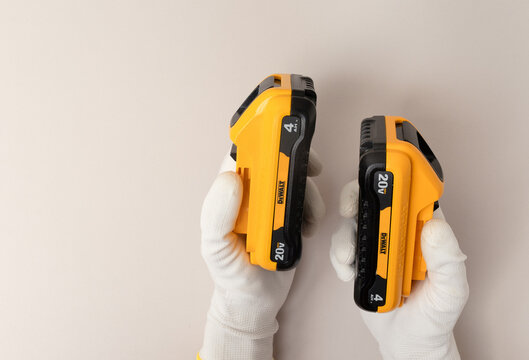 Kharkiv, Ukraine, July 12 2026: Illustrative Editorial of Gloved Hands Holding Two DeWalt 20V MAX Battery Packs.