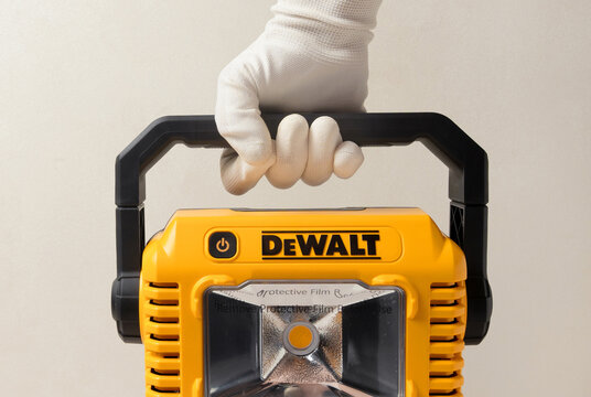 Kharkiv, Ukraine, July 12 2026: Illustrative Editorial of  Gloved Hand Holding DeWalt DCL077 LED Work Light by Handle.
