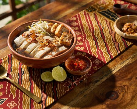 indonesian bakso ayam or chicken meatball soup served in a ceramic bowl with fried tofu and bean sprouts.