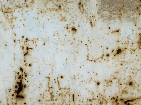 Speckled rusty metal texture background. Old white painted iron surface with pitted rust stains and corrosion dots. Distressed industrial backdrop.