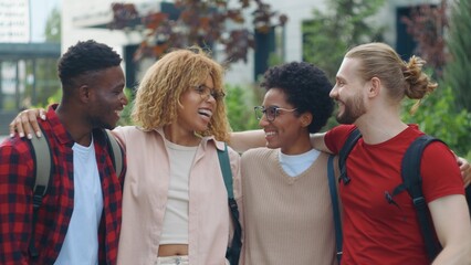 Obraz premium Group of four multiracial students laughing happy hugging in city multiethnic friends candid humorous having fun smiling laugh hug cuddling friendship high school university college education concept