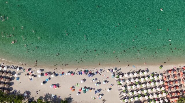 Drone shot revealing crowd of tourist at Pefkochori beach on a sunny day in summer, Sunloungers and inflatable waterpark, Halkidiki, Drone shot