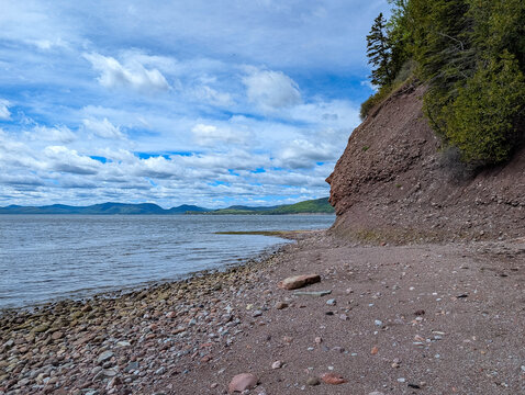 Gaspesie, Quebec, 07 June 2026 : A natural rock formation resembling a human face overlooks a rocky shore and calm water.