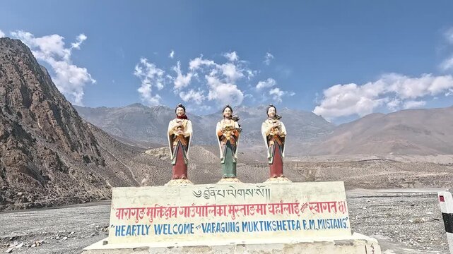 dolly in Three Buddhist deity statues with welcome sign, mountains beyond, landmark installation Nepal