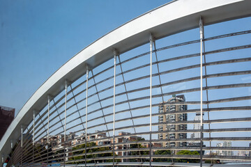 Pedestrian bridge arch with metal rails framing apartment towers in Shanghai, China © Rawf8