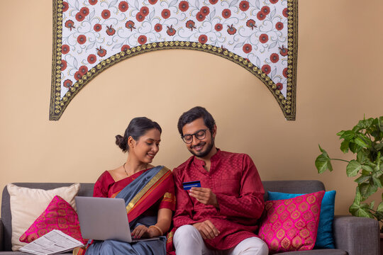 Portrait of happy young couple shopping online through laptop using credit card at home